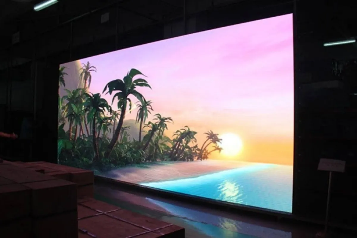 Painel de LED indoor exibindo imagem de pôr do sol com coqueiros e mar, em ambiente interno com iluminação controlada.