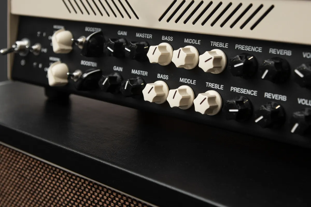 Close-up dos botões e controles de equalização (Bass, Mid, Treble) de um cabeçote de amplificador ou sistema de som de guitarra vintage.