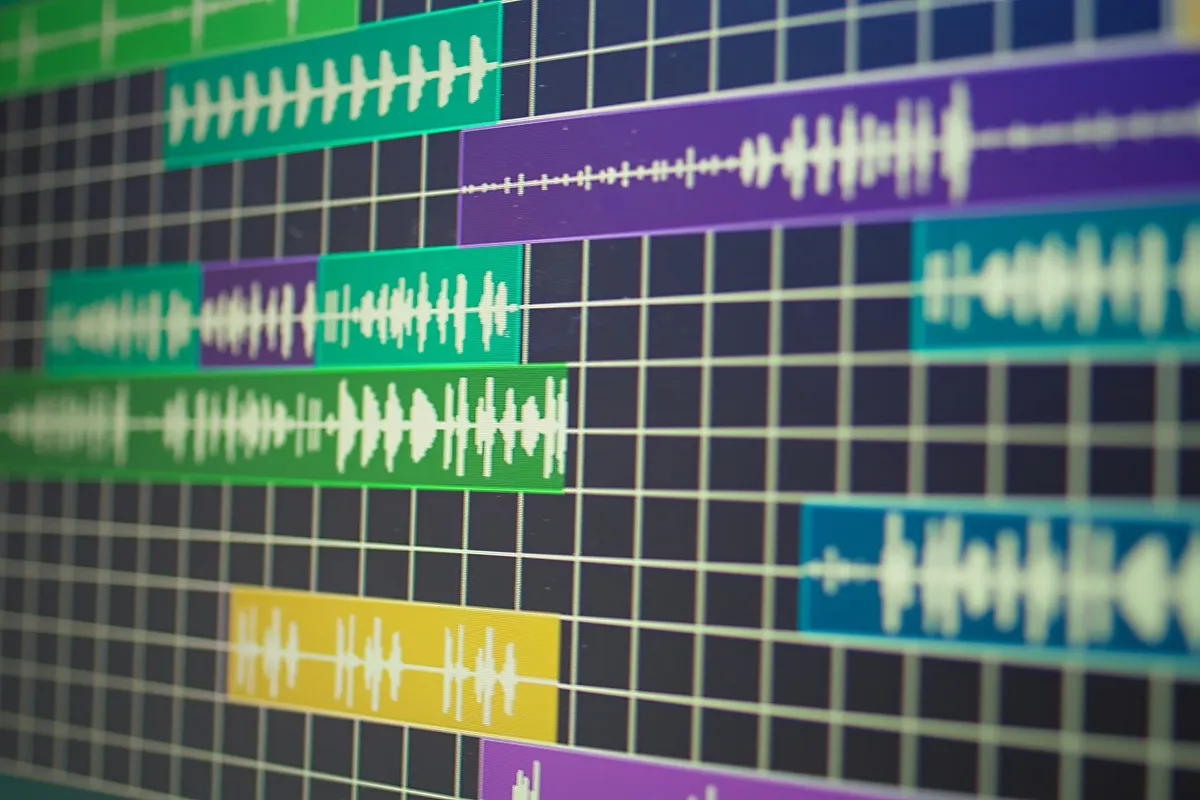 Tela de software de edi??o de ?udio exibindo trilhas com formas de onda coloridas em verde, amarelo, azul e roxo.