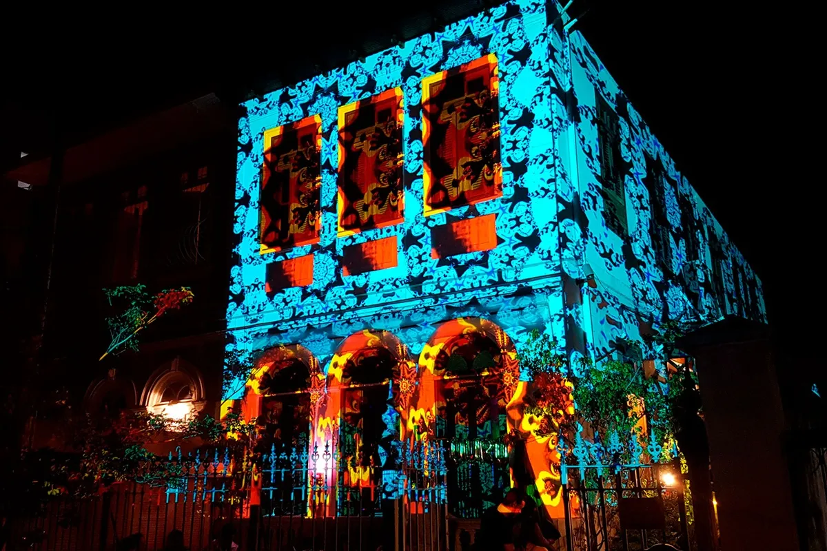 Fachada de prédio histórico em Buenos Aires iluminada com projeção mapeada colorida, exibindo padrões geométricos e artísticos durante a noite.