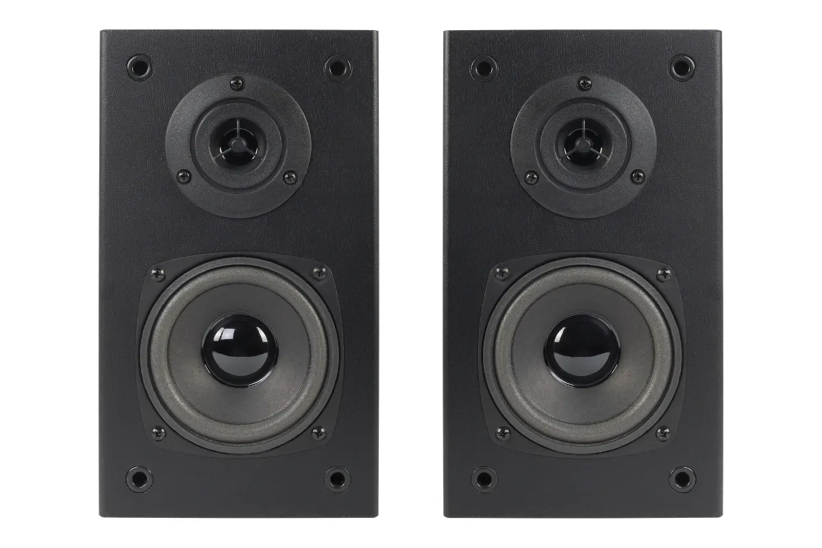 Duas caixas de som compactas pretas posicionadas lado a lado sobre fundo neutro.