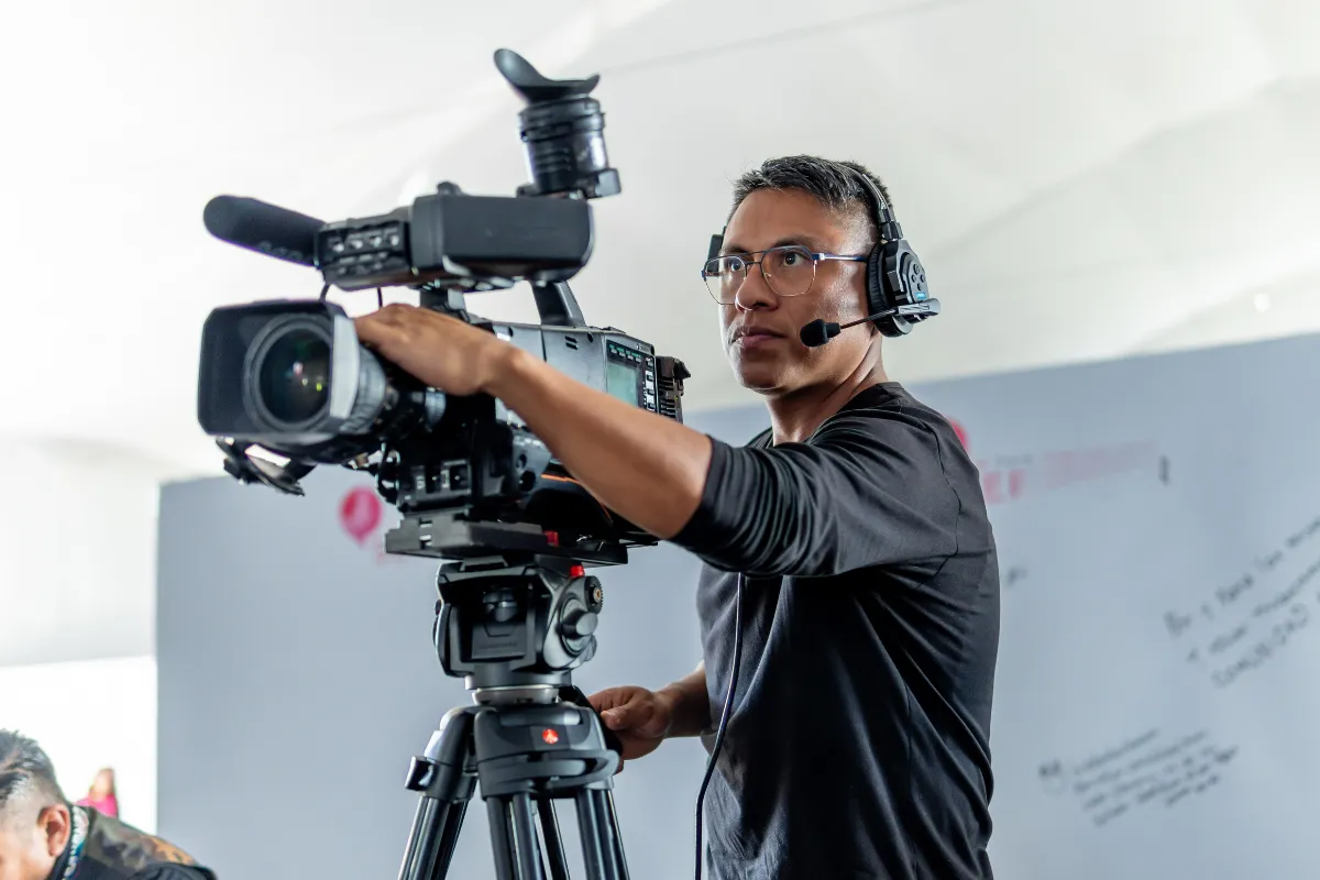 Operador usando fone de ouvido ajustando câmera profissional durante gravação em ambiente interno
