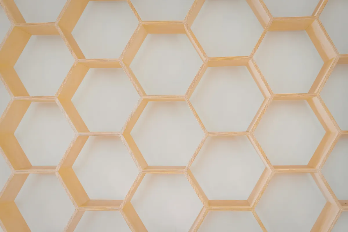 Parede com estrutura decorativa formada por vários nichos hexagonais em tom claro, criando um padrão semelhante a uma colmeia.