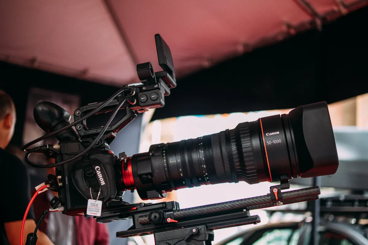 Câmera profissional de cinema com lente teleobjetiva montada em suporte durante gravação em set de filmagem.