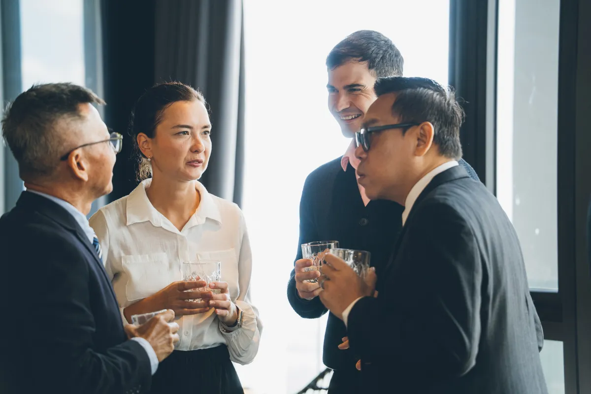 Grupo de profissionais conversando e interagindo durante um evento corporativo em ambiente interno