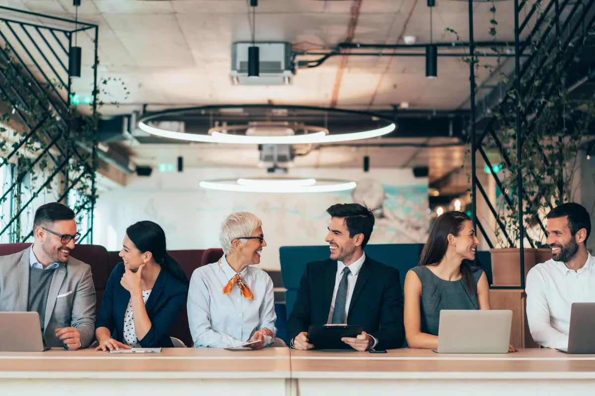 Grupo de profissionais sentados em mesa participando de um painel de discussão em ambiente corporativo