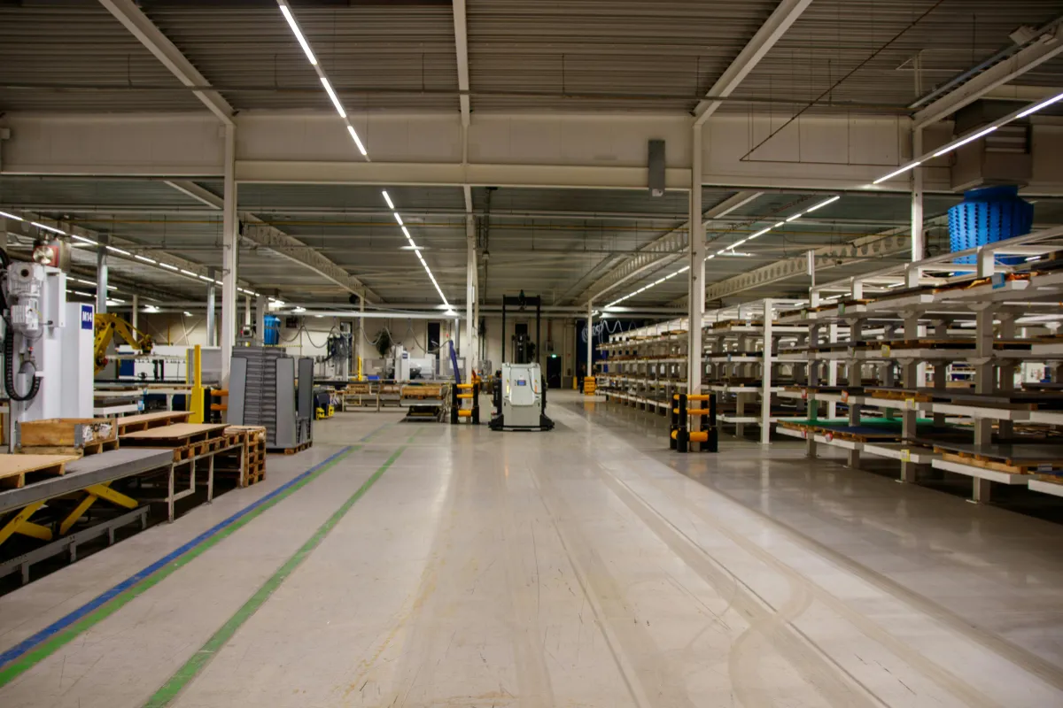 interior de galpao industrial com luminarias lineares no teto iluminando area de producao