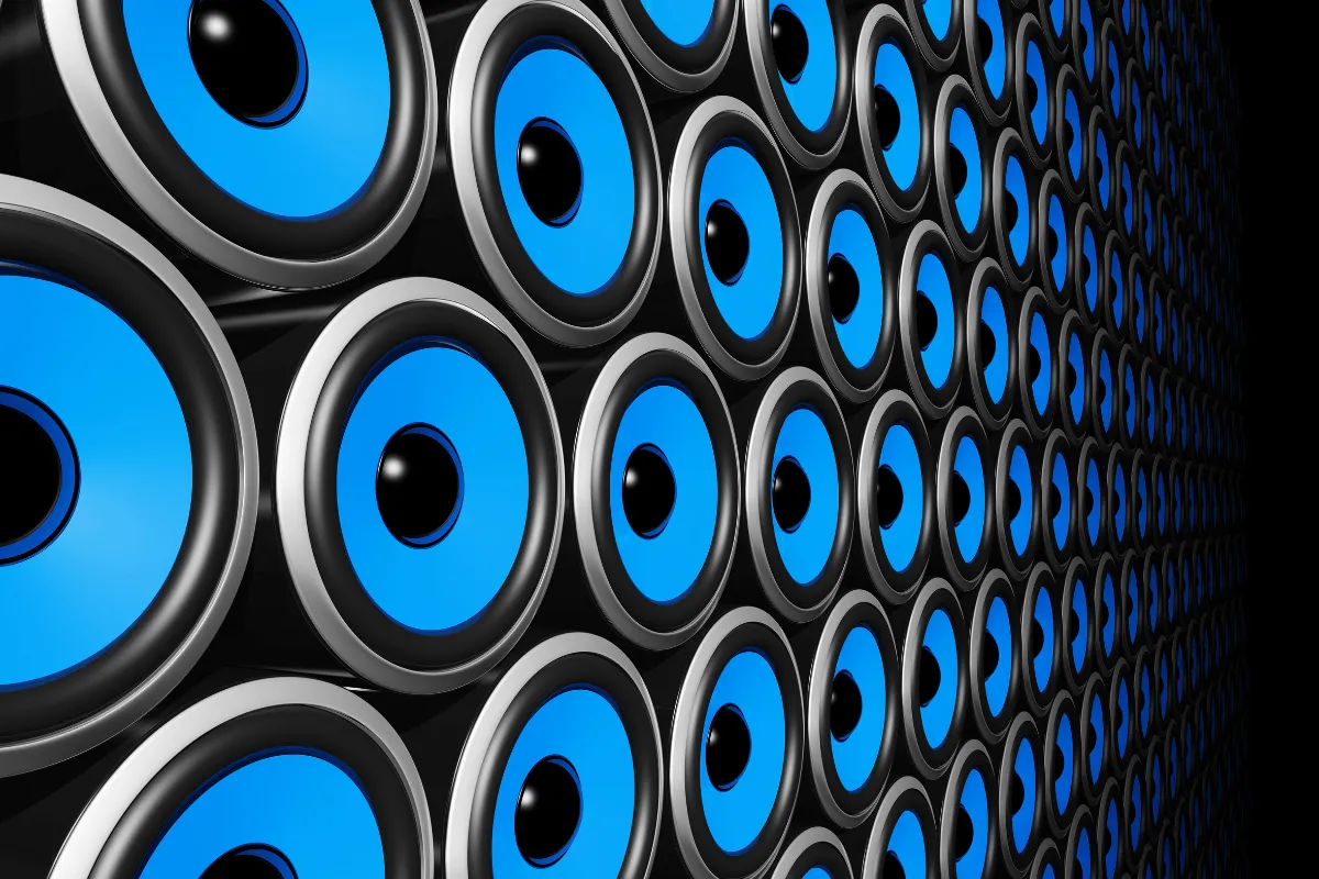 Parede com várias caixas de som azuis organizadas em padrão repetido formando sistema de áudio