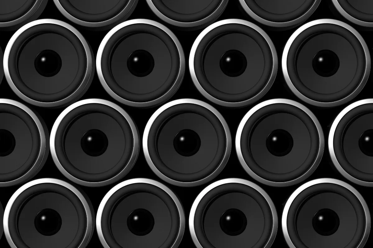 Várias caixas de som pretas alinhadas formando um painel com alto-falantes circulares